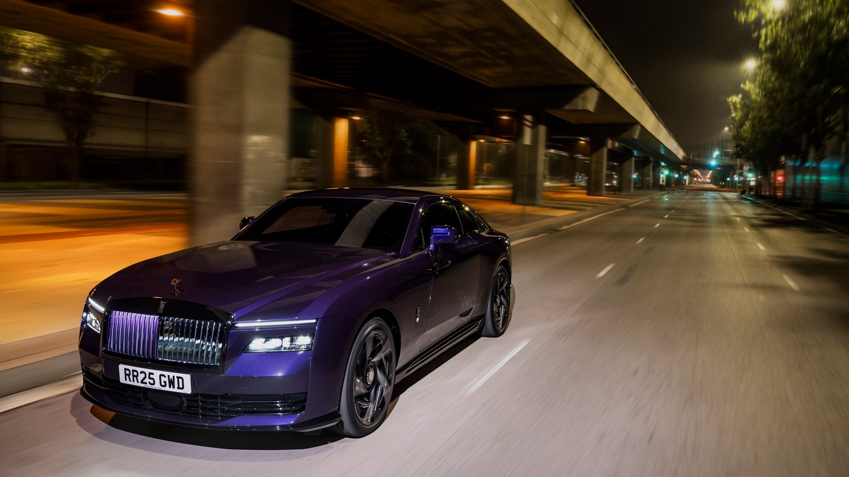 Sleek purple Rolls-Royce Black Badge Spectre driving down a Baltimore street at night